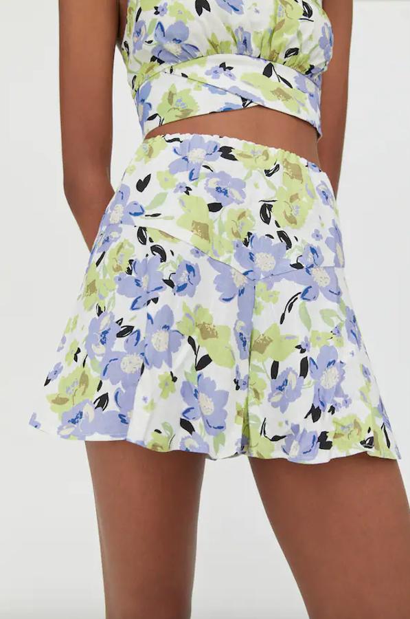 Con detalle de canesú y volantes en el bajo, esta falda pantalón blanca con estampado de flores en lila y verde pastel es de Pull&Bear, tiene un precio de 17,99 euros y solo queda en la talla XL, y se está agotando.