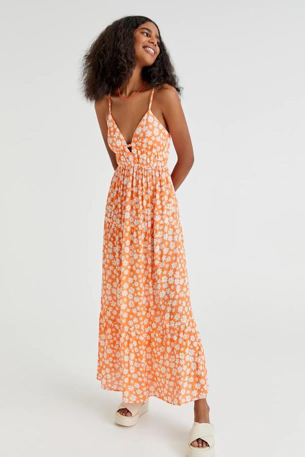 En color naranja y con flores blancas, este vestido largo con detalle de goma en la cintura cuenta con escote de pico y nudo en la espalda. Es de Pull & Bear y tiene un precio de 29,99 euros.