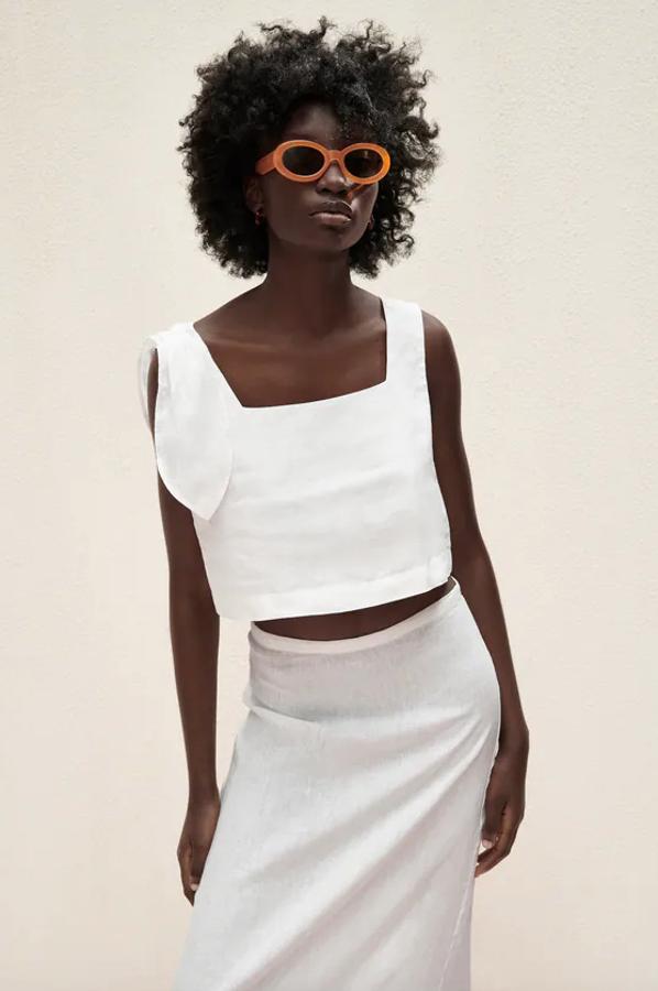 Diseño corto confeccionado en lino para este top de Zara con escote recto y tirantes anchos que viene con detalle de lazada en el mismo tejido. Disponible entre las tallas XS y XL, cuesta 25,95 euros.