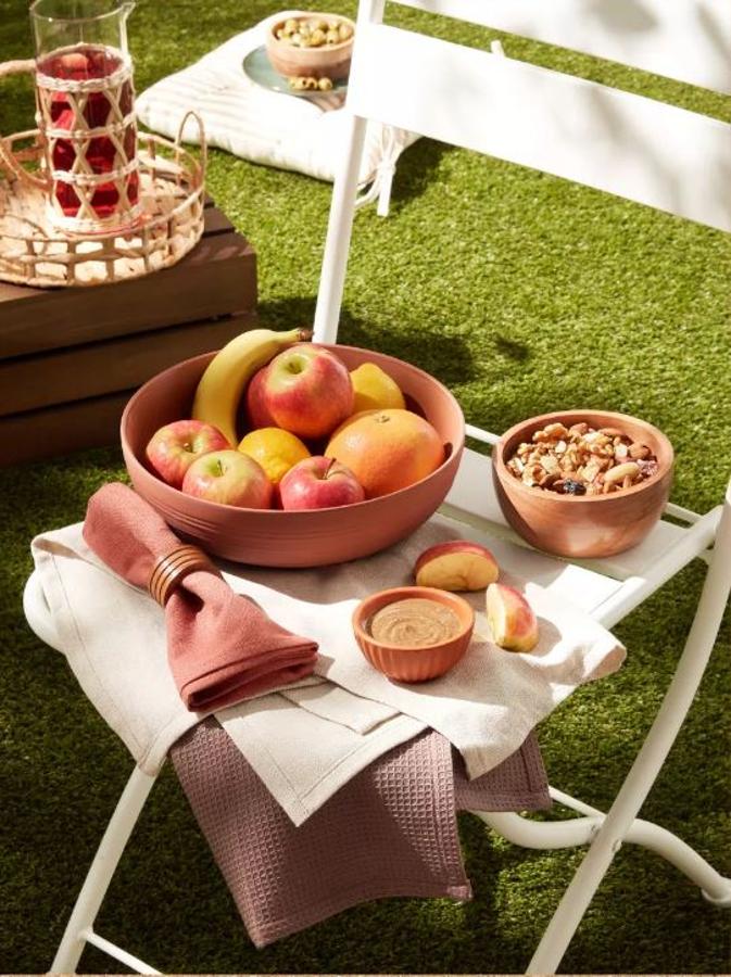 El verano y el buen tiempo hacen que los mejores planes se hagan al aire libre. Por eso, los jardines y terrazas se convierten en nuestra zona favorita de la casa. En Primark Home hemos encontrado el menaje para exteriores más bonito y barato: la manta de pícnic cuesta 12 euros, el pack de 2 cojines para sillas 9 euros, la bolsa nevera pequeña, 5 euros; y los boles de madera están disponibles desde 4 euros..