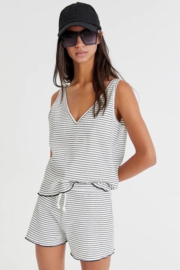 Este top de canalé de color blanco con rayas finas negras cuenta con escote de pico y detalle de rizos en contraste con el bajo. Tiene un precio de 12,99 euros.