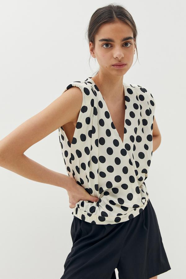 En color blanco con estampado de lunares negros, esta blusa sin mangas, con hombreras y cuello de pico está confeccionada en tejido satinado y tiene un precio de 13,99 euros. Podemos encontrarla en las tallas S, M y L.