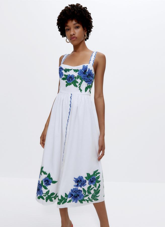 Este vestido midi de color blanco con bordados florales en punto de cruz en azul y verde cuenta con tirantes anchos y escote recto. Tiene un precio de 129 euros.