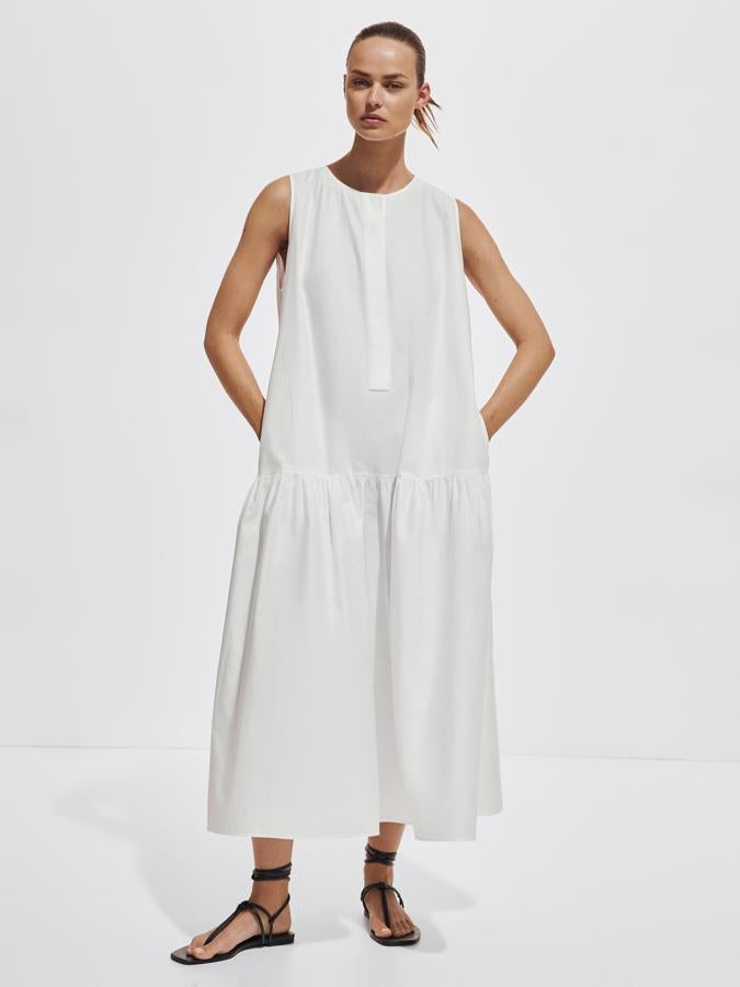 En color blanco, de corte holgado y cuello redondo, este vestido blanco confeccionado al 100% en algodón viene con dos bolsillos laterales y sin mangas. Con botonadura frontal en el escote, cuesta 79,95 euros y podemos encontrarlo entre las tallas XS y L.