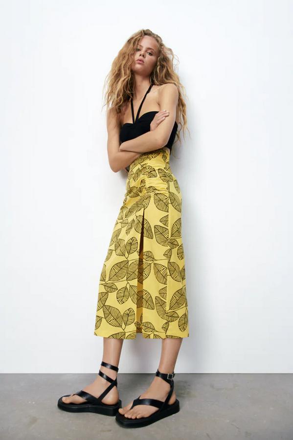 Confeccionada en tejido con mezcla de lino, esta falda de tiro alto en color amarillo con estampado de hojas a contraste en negro viene con detalle de frunce elástico en delantero y abertura en bajo hasta por encima de la rodilla. Con un precio de 25,95 euros, está disponible entre las tallas XS y L. 