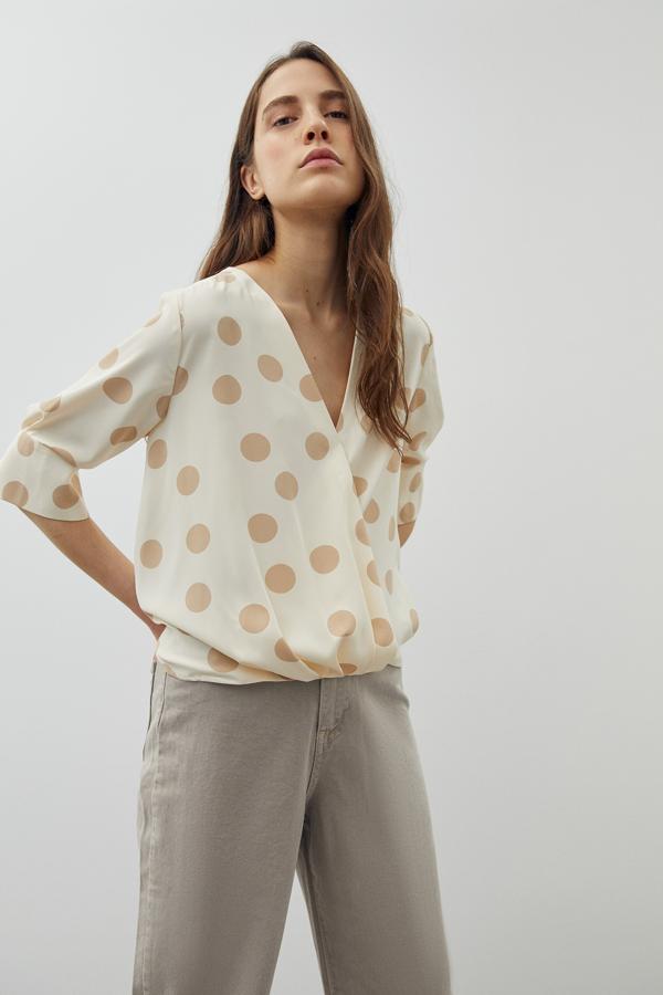 En crema con lunares beige, o a la inversa, esta blusa de bajo asimétrico y con escote de pico costaba 17,99 euros y ahora podemos comprarla por 13,99 euros en las tallas S, M y L.
