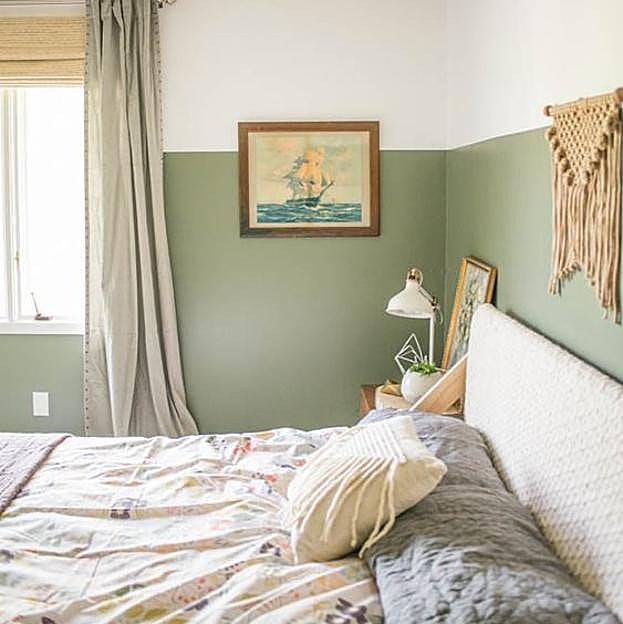 Dormitorio con ropa de cama de flores, y pared al estilo 'half-painted' en verde y blanco.