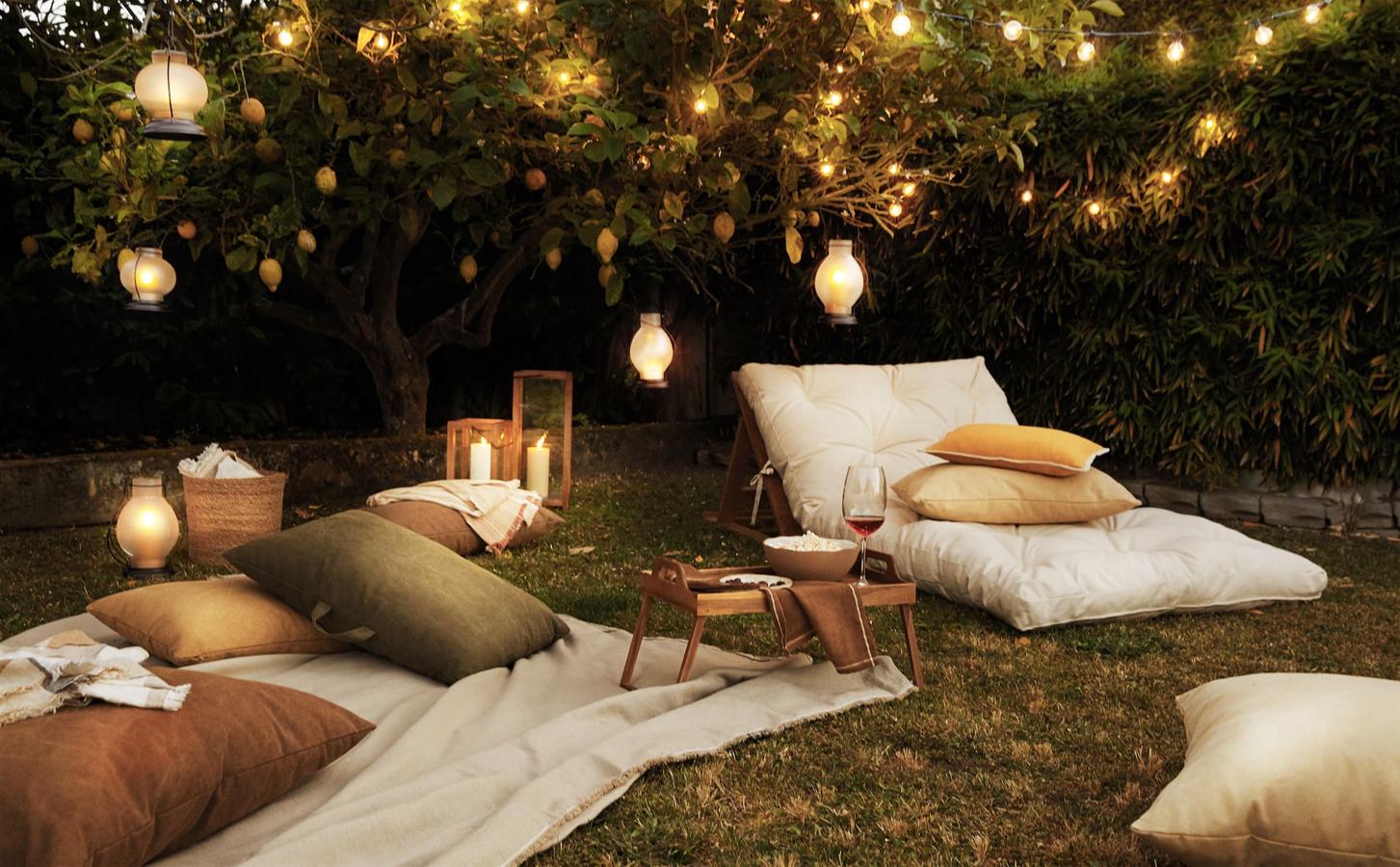 Por supuesto, para disfrutar de nuestro cine de verano tenemos que estar bien cómodas, así que necesitamos este futón confortable (129 euros la colchoneta y 99 euros el soporte de madera), unos cojines bien mulliditos (desde 14.99 euros) y unos farolillos que nos den luz indirecta y cálida (desde 25.99 euros).