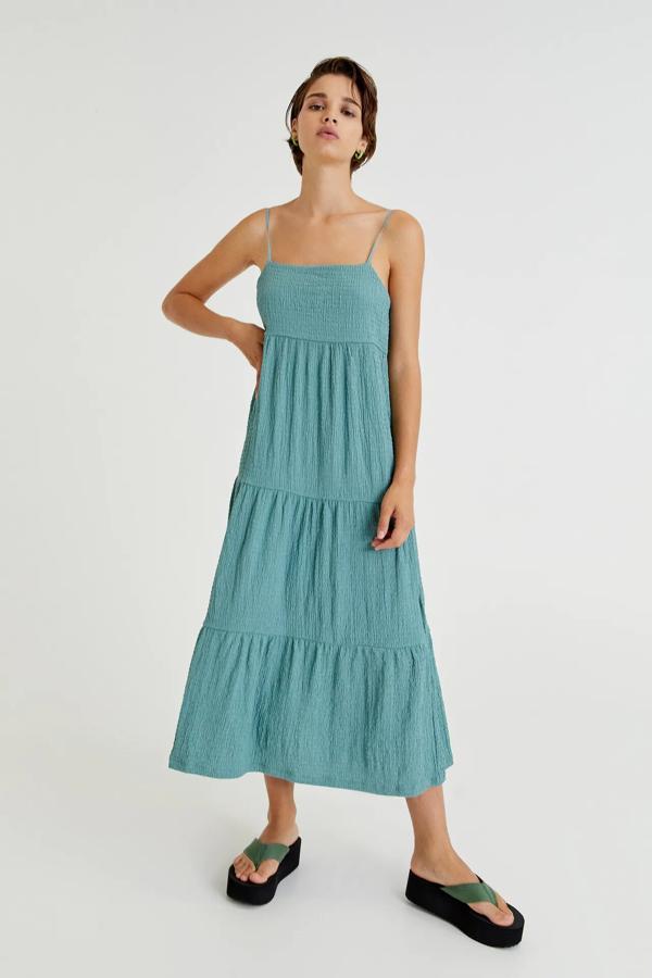 En color verde azulado, este vestido largo con tirantes finos y diseño de volantes horizontales es de Pull & Bear y tiene un precio de 22,99 euros.