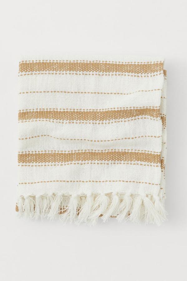 Para las terrazas de estilo natural, y en tonos claros, te recomendamos esta manta de H&M Home. Cuesta 34,99 euros.