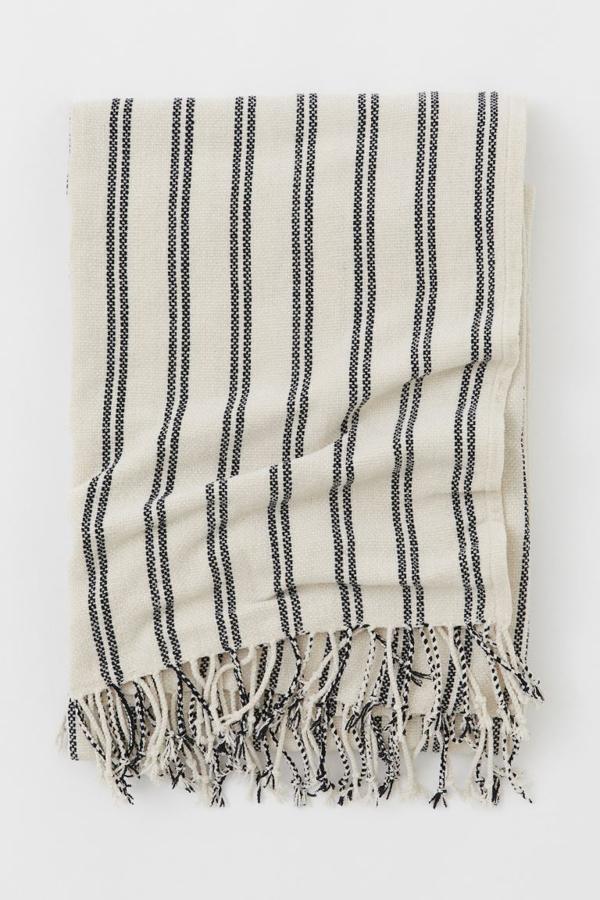Con rayas, en beis y negro. Esta manta de H&M Home ahora está rebajada y cuesta 10,99 euros.