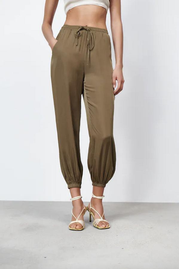 Diseño fluido y tiro alto para este pantalón de cintura elástica ajustable con cordón que podemos encontrar en negro o en color aceite. De 22,95 euros ha pasado a costar 12,99 euros. 