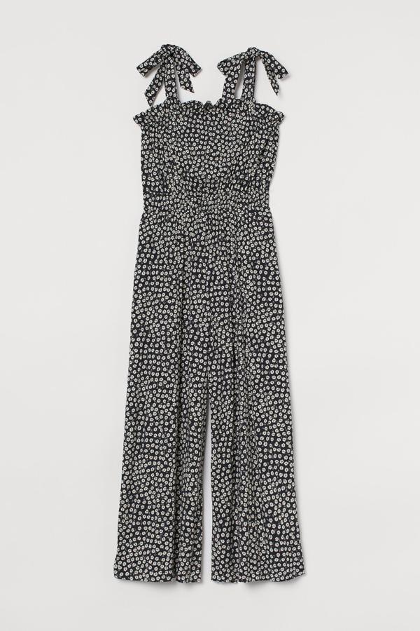 En color negro con estampado de flores en blanco, este mono tobillero con ribete de volantes y tirantes anchos es de H&M y tiene un precio rebajado de 11,99 euros.