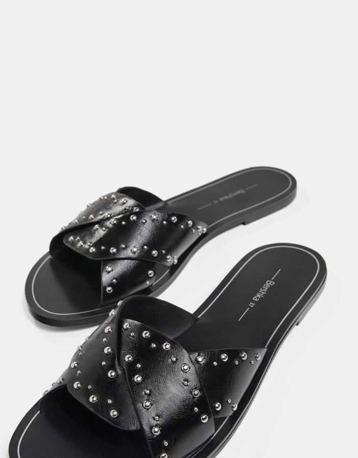 Empeine de diseño cruzado en color negro con detalle de tachas en diferentes tamaños para estas sandalias planas que de 19,99 euros han pasado a costar 12,99 euros y están disponibles entre los números 35 37 y en el 39 y el 40.