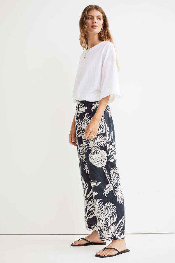 En color negro con estampado de palmeras, este pantalón en lino vaporoso cuenta con elástico revestido y ribete de volante en la cintura y tiene un precio de 29,99 euros. 