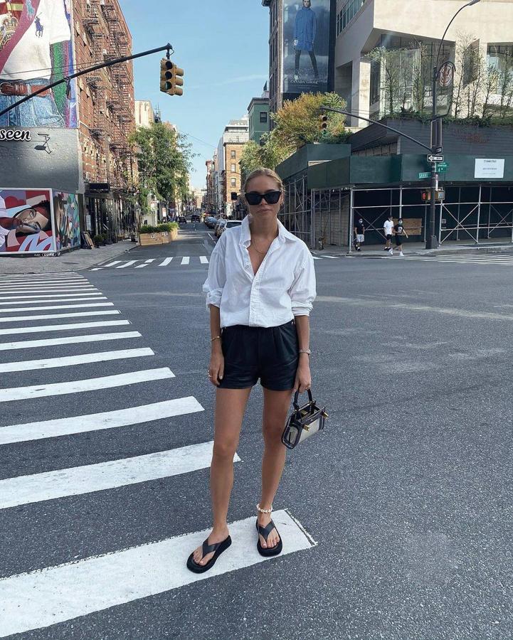 Un look muy sencillo que se basa en una camisa básica blanca remangada y unos 'shorts' estilo sastre en negro. Para hacerlo más veraniego e informal, le añade un mini bolso y unas sandalias planas destalonadas. Y, el detalle de la tobillera playera es genial.