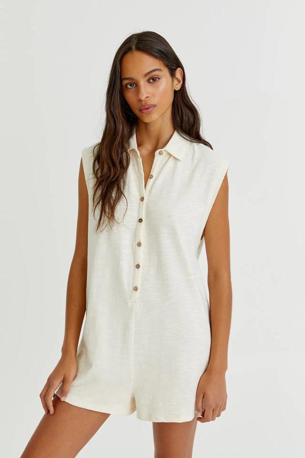 Con cuello tipo polo y botones delanteros, este mono corto de color crudo y mangas sisa tiene un precio de 17,99 euros.