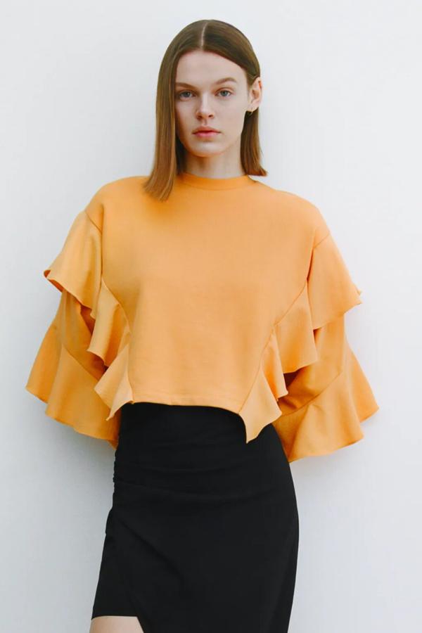 Esta sudadera corta en color naranja con cuello redondo y volantes tiene un precio rebajado de 3,99 euros (antes 25,95 euros).