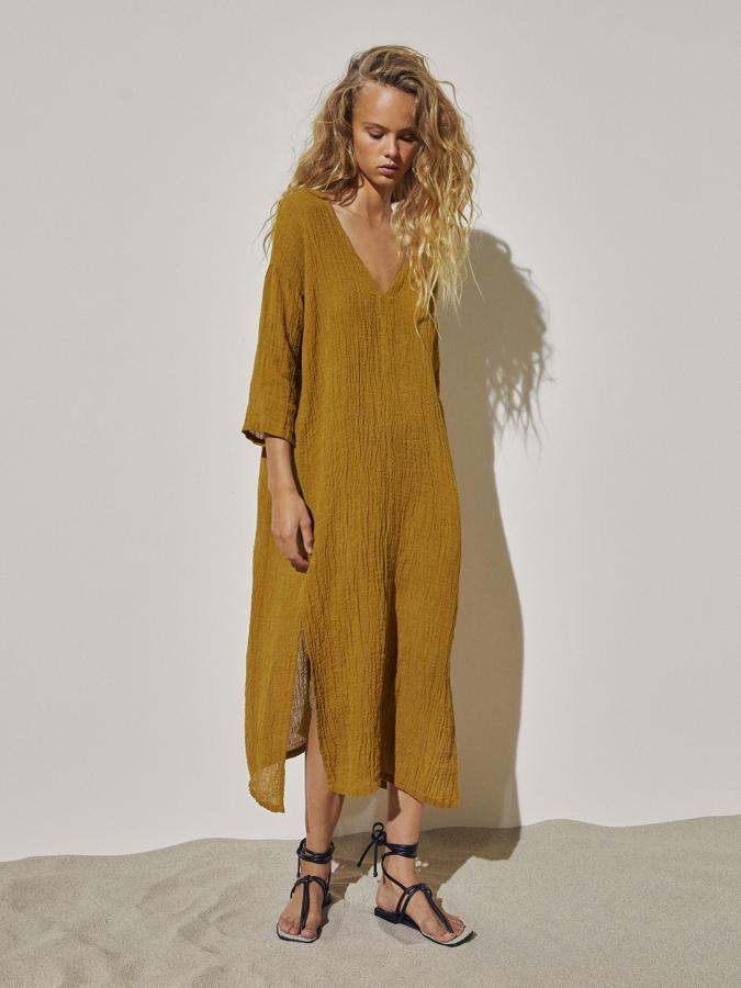 En tono aceite, este vestido confeccionado en lino y con corte fluido cuenta con aberturas en los laterales y tiene un precio de 99,95 euros.