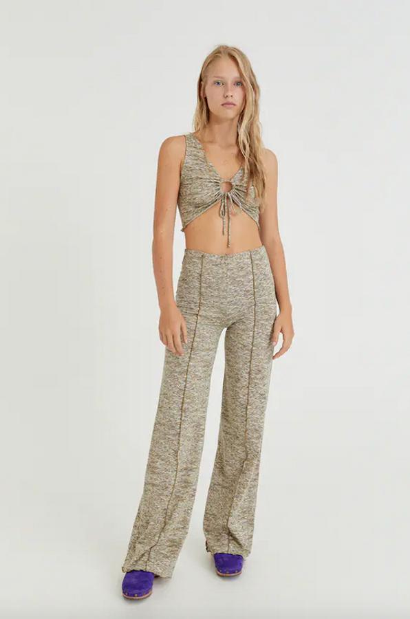En verde oliva jaspeado, este conjunto de Pull&Bear está compuesto por un top cropped con diseño cut out en el pecho con arandela y funces, que tiene un precio de 12,99 euros, y unos pantalones de diseño campana con costuras vistas y cintura elástica que podemos comprar por 19,99 euros. 