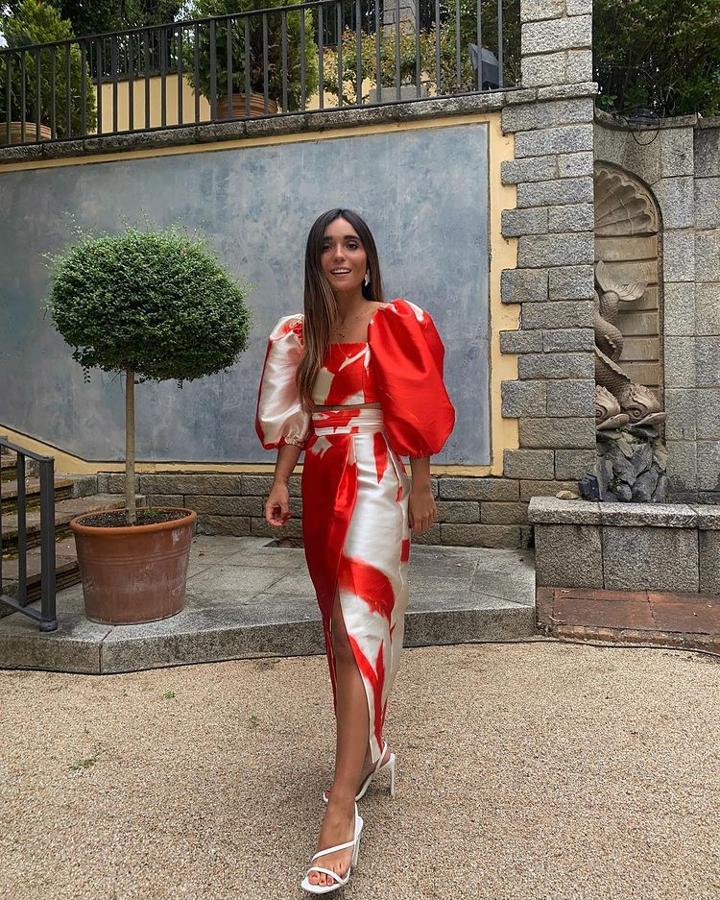 La influencer se decanta por un conjunto estampado, compuesto por crop top de manga abullonada y falda de cintura alta con abertura. Como calzado, sandalias de tacón, en blanco.