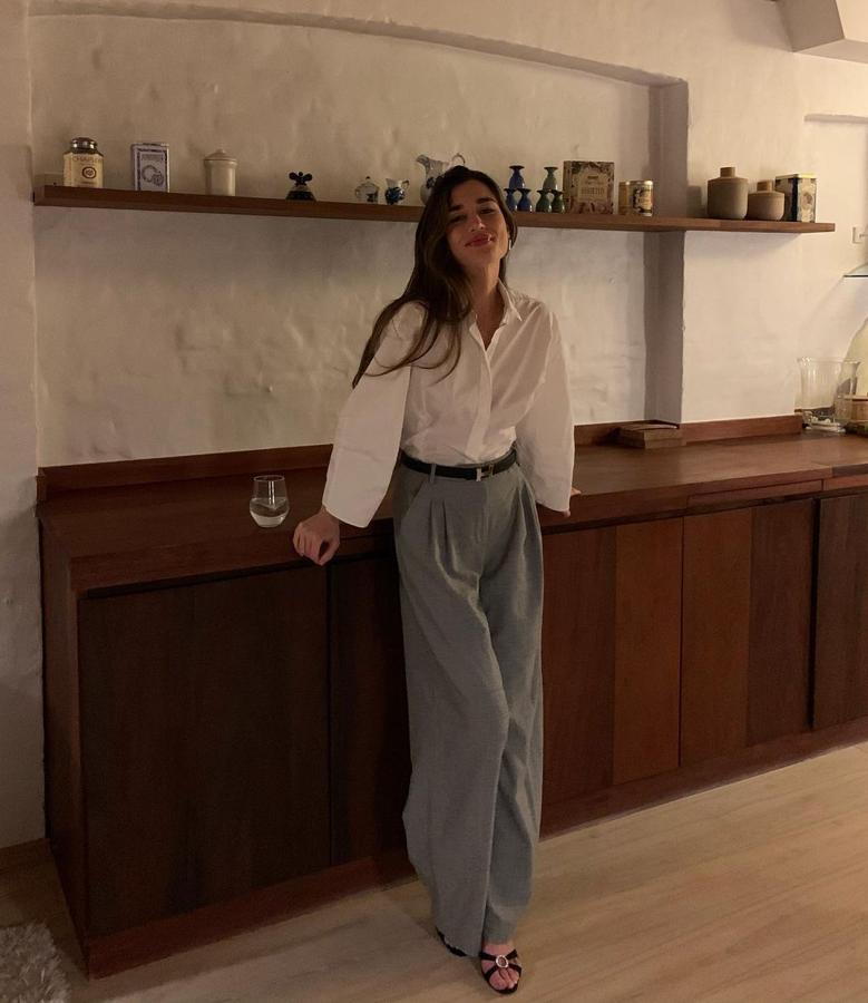 Un look de oficina por excelencia. Camisa de popelín, pantalón de pernera ancha con pinzas, cinturón y sandalias de tacón bajo. Elegantísimo si lo acompañamos de unos pendientes bonitos.