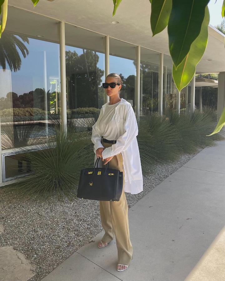 Camisa oversize y camiseta básica, ambas en blanco, junto a pantalón beige y sandalias. Al estilo 'model off-duty', en tonos neutros.