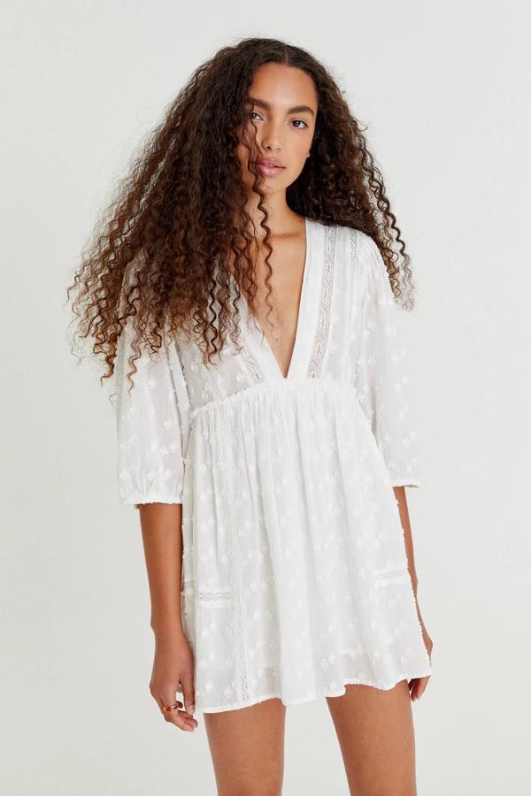 En color blanco, este mono corto con detalle de puntillas y volantes cuenta con escote de pico y manga francesa. Confeccionado en 100% algodón, tiene un precio de 25,99 euros.
