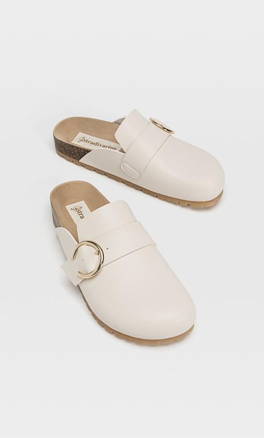 Con detalle de tira y hebilla en el empeine, estos zuecos en color crudo de Stradivarius tienen suela en combinación de materiales y podemos encontrarlos entre los números 35 y 41 por 25,99 euros.