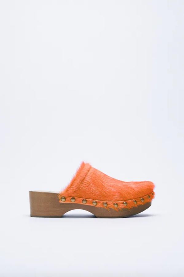 En piel con pelo y detalle de tachas, estos zuecos naranjas de Zara con suela en combinación de materiales tienen un precio de 99,95 euros y están disponibles entre los números 36 y 41.