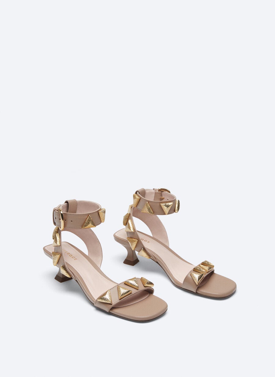 Con cierre de pulsera con hebilla y apliques dorados chapados en oro, esta sandalia de Uterqüe en color maquillaje con tacón de 5 centímetros tiene un precio de 129 euros y está disponible entre los números 35 y 40.