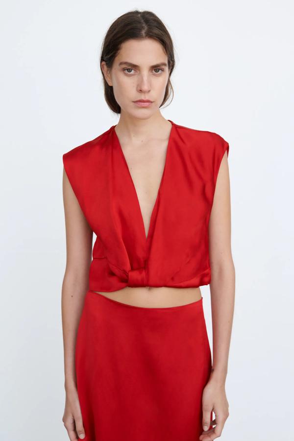 De color rojo y efecto satinado, este top con escote de pico y detalle de nudo en la parte delantera cuenta con cierre lateral con cremallera oculta y tiene un precio de 29,95 euros.