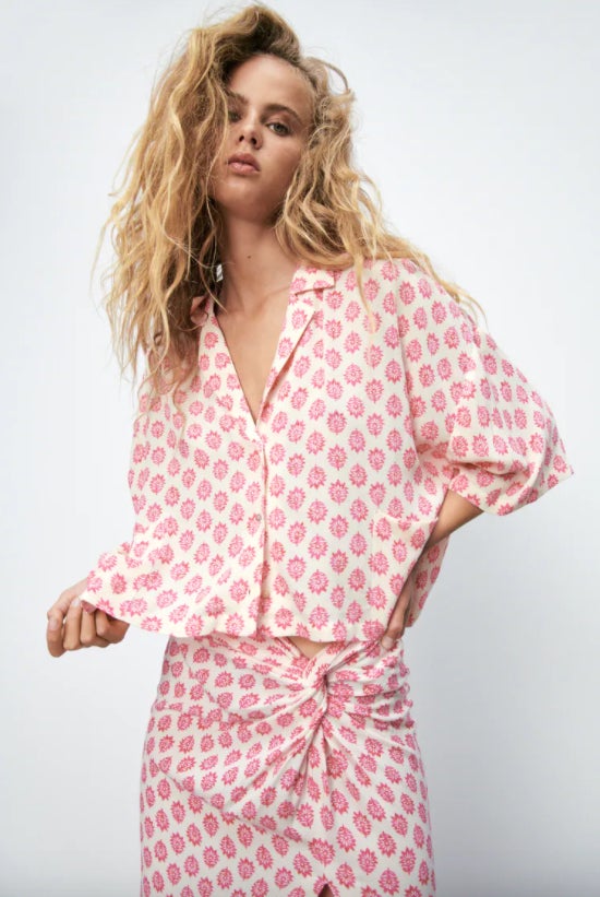 Con escote de pico y mangas cortas, esta camisa con bolsillos de plastrón laterales es de Zara. En color crudo con estampado floral en rosa, tiene un precio de 19,95 euros y está disponible entre las tallas M y XXL. 