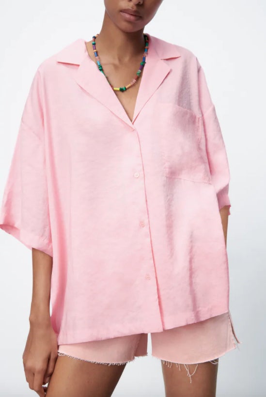 Diseño oversiza de cuello solapa y mangas cortas con bolsillo de plastrón en la pechera y bajo con aberturas laterales. Tiene un precio de 22,95 euros y está disponible entre las tallas XS y XXL. 