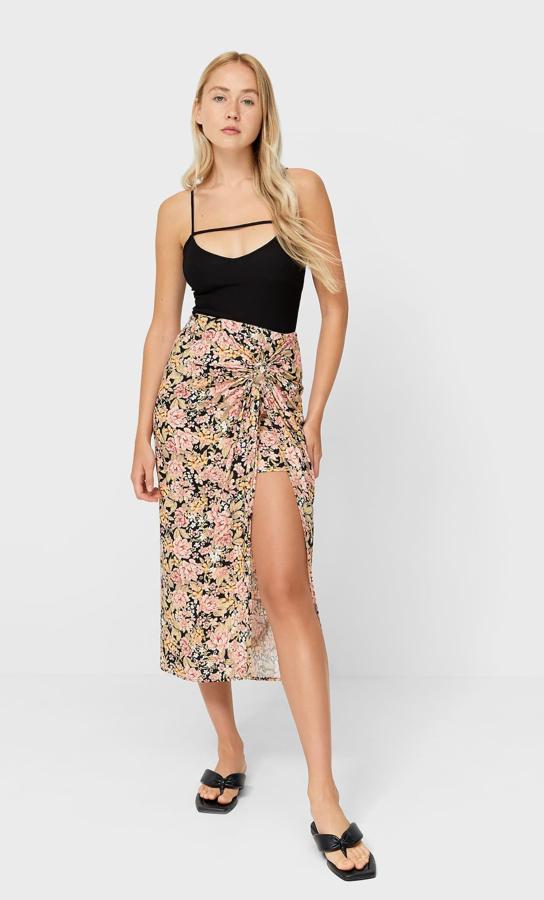 De tiro alto con nudo delantero, esta falda midi rústica en color negro con estampado de flores en tonos rosados y tostados es de Stradivarius y cuesta 19,99 euros. Está disponible únicamente en las tallas 34, 36 y 40.