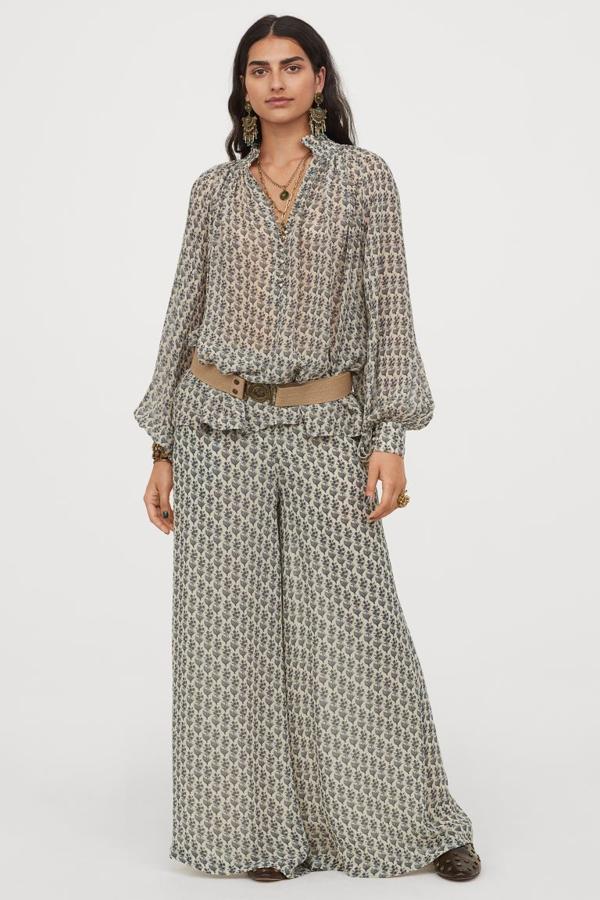 Diseño holgado en crepé de gasa para este pantalón con suave caída y estampado en tonos azules sobre color crema. De talle alto y bolsillos laterales, cuesta 49,99 euros. La blusa a juego con volumen y escote de pico con botones revestidos tiene un precio de 49,99 euros.