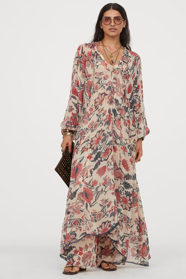 Diseño holgado largo para este vestido en crepé de gasa fluida con estampado floral, escote de pico con tiras de anudar y cordón de ajuste en escote y cintura. Tiene mangas largas amplias con cordón de ajuste en los puños, bajo asimétrico con ribete de pompones y laterales algo más largos. Tiene un precio de 59,99 euros.