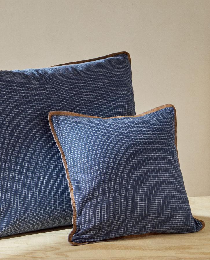 Con estampado de cuadros en color azul y extremos a contraste en marrón, esta funda de cojín de algodón mide 70x90 centímetros y tiene un precio rebajado de 9,99 euros.