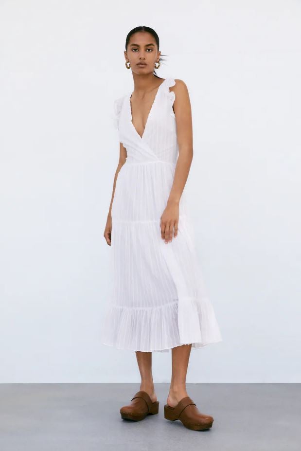 Este vestido midi de lino rústico en blanco de Zara, con escote a la espalda, cuesta 39.95 euros y es perfecto para tus looks más fresquitos y favorecedores.