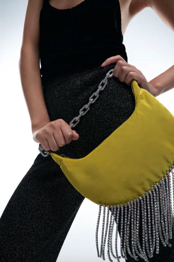 En verde lima, este bolso de hombro con cuerpo de satén es de Zara y viene con detalle de flecos de brillos en el bajo, interior forrado y asa de hombro de cadena maxi con brillos. Con cierre de cremallera, cuesta 39,95 euros. 