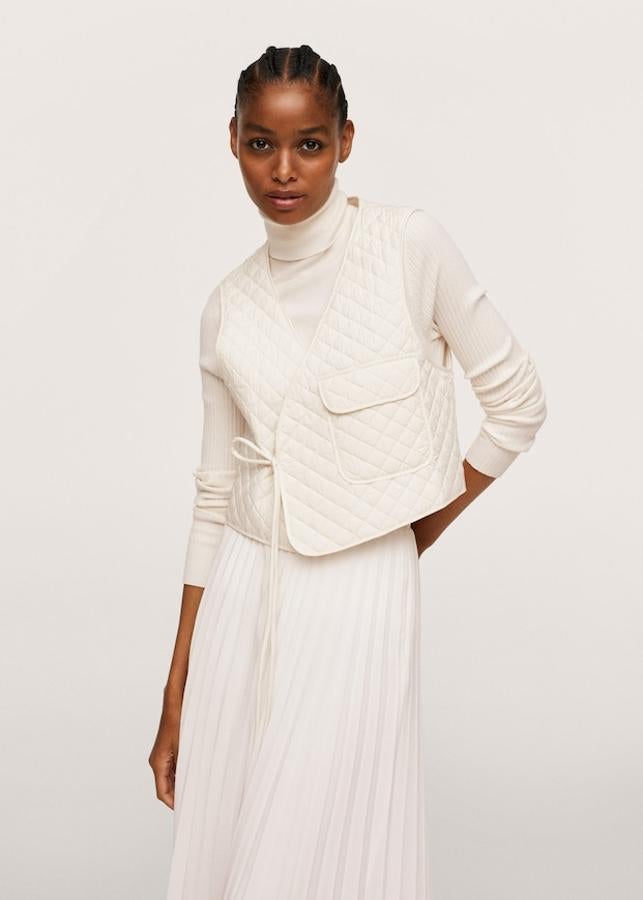 En un precioso color crudo, este chaleco acolchado de Mango de diseño recto con cuello de pico y cierre de lazo a tono cruzado tiene un precio de 25,99 euros y está disponible en las tallas XS-S y M-L.