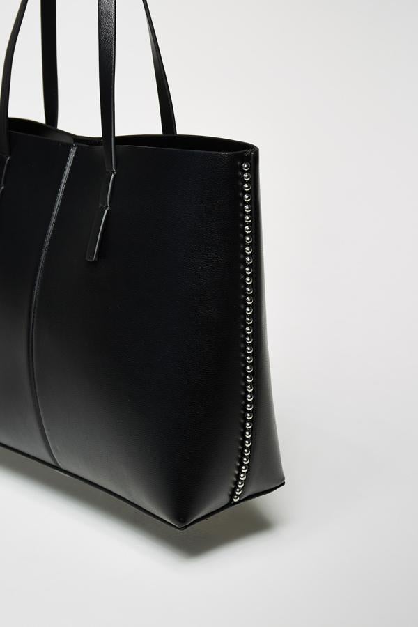 Uno de los más originales es este bolso shopper de Sfera con detalle de bolitas plateadas en los laterales. Tiene cierre superior de imán y asas de hombro y cuesta 17,95 euros. 