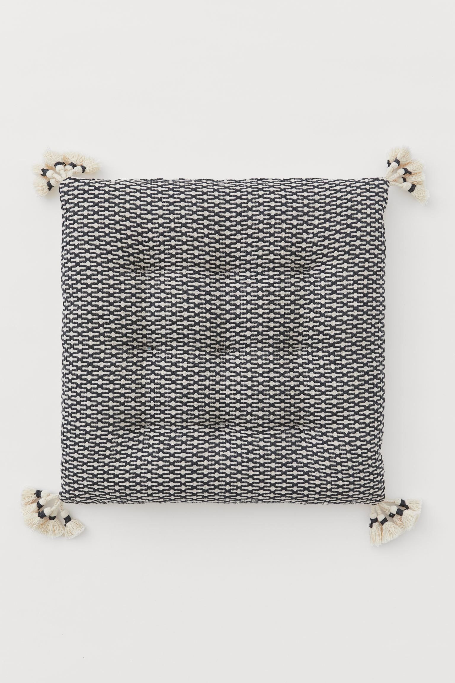 Y este cojín estampado con borlas, es perfecto para un toque de color en contraste en un dormitorio de estilo minimalista. Cuesta 8.99 euros en las rebajas de H&M Home.