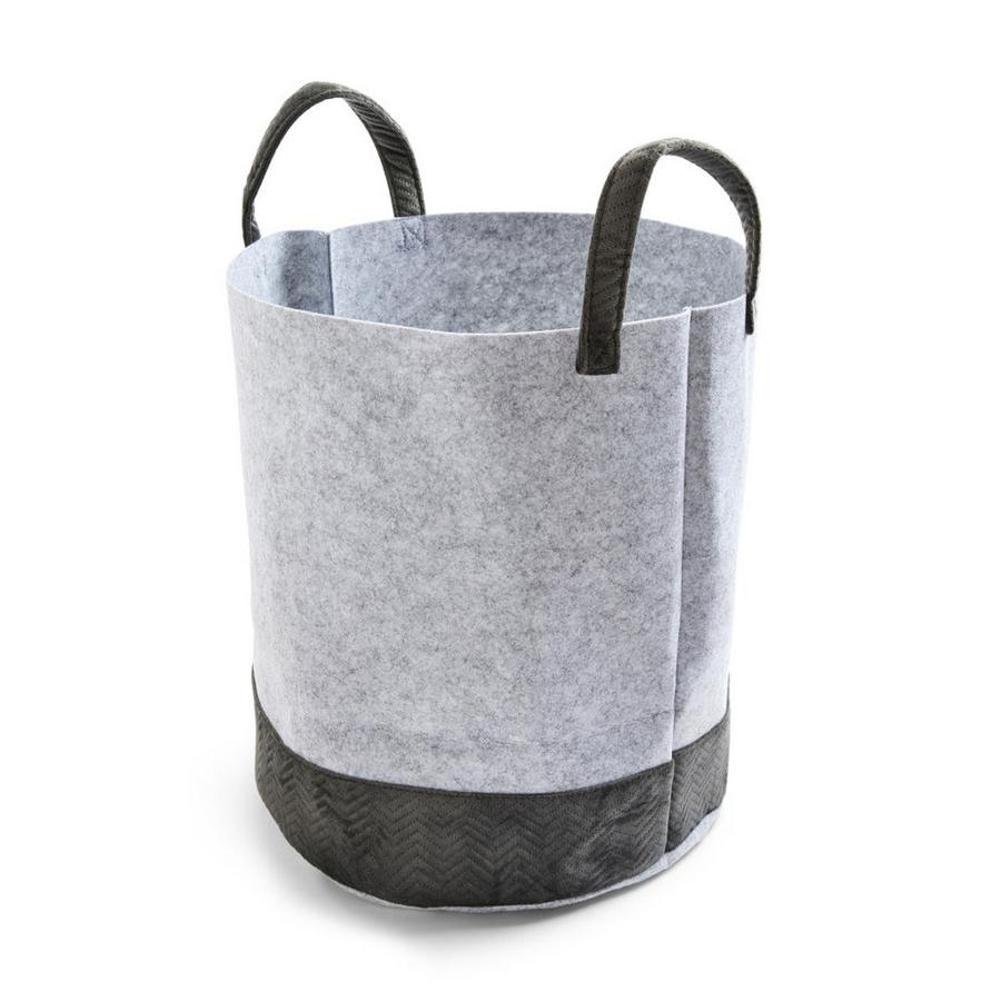 En fieltro y terciopelo y en color gris y negro, este cesto para la ropa sucia con asas a contraste cuesta 6 euros. 