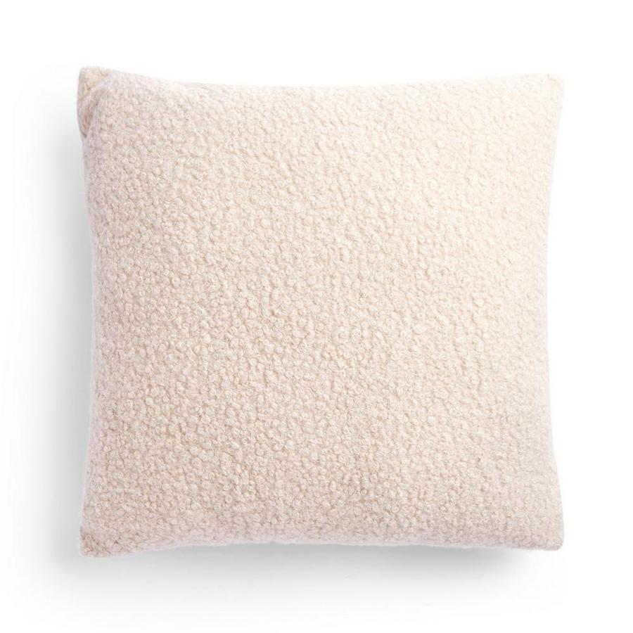 Para los sofás, las sillas o la cama, este cojín de tejido rizado en color marfil tiene un precio de 8 euros. 