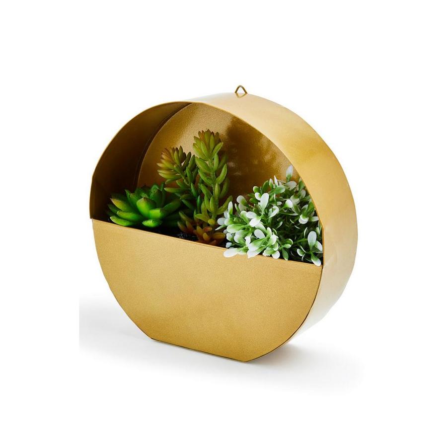 Ideal para plantas pequeñas como cactus y ponerle un toque original a tus paredes, este macetero circular colgante en dorado cuesta 9 euros.