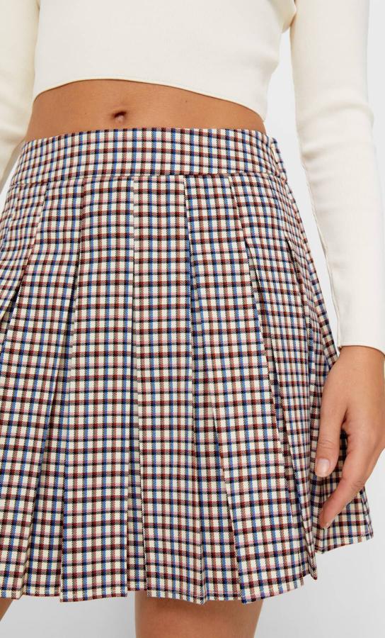 Con estampado de cuadros mini en naranja y azul o en formato normal en blanco y negro, esta minifalda de tablas de Stradivarius de tiro alto con cremallera oculta tiene un precio de 19,99 euros y está disponible entre las tallas XS y XL. 