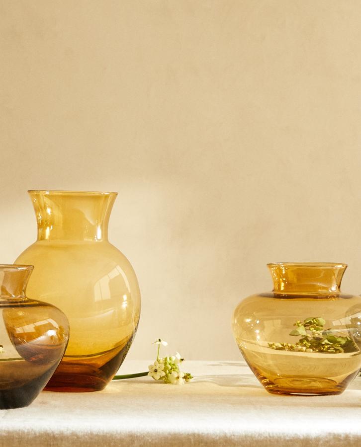 Este jarrón de vidrio oscuro y está disponible en varios colores y medidas: 17x20 centímetros (19,99 euros) y 30x18 centímetros (29,99 euros).