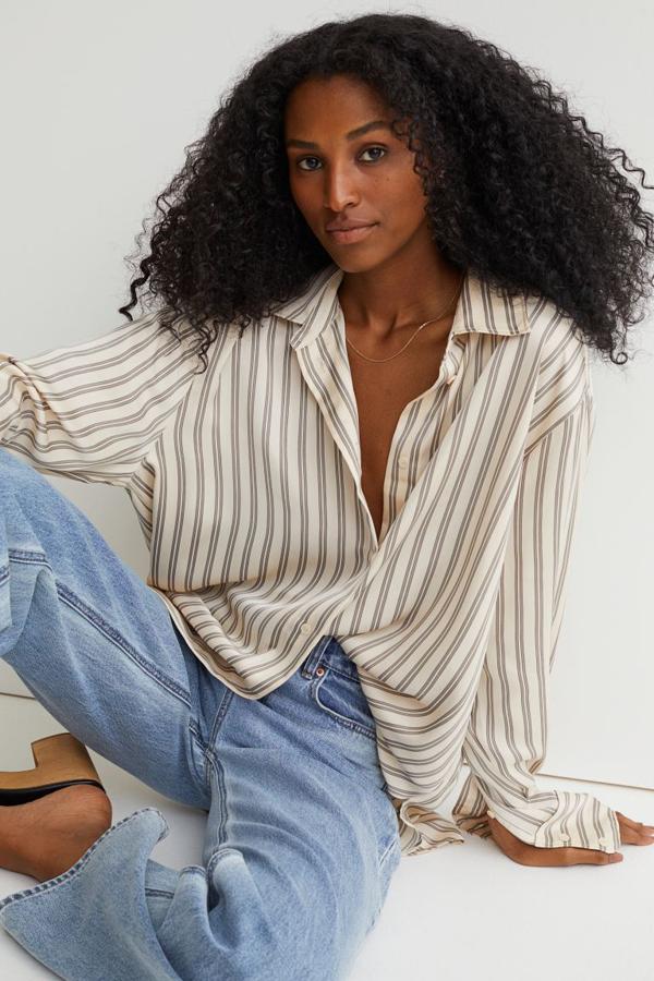 De venta exclusiva en la web de H&M, esta camisa con ligero brillo en beige con rayas negras es de corte relajado, tiene cuello clásico y cierre frontal de botones. Con diseño de hombros ligeramente caídos y bajo ligeramente redondeado, cuesta 19,99 euros.