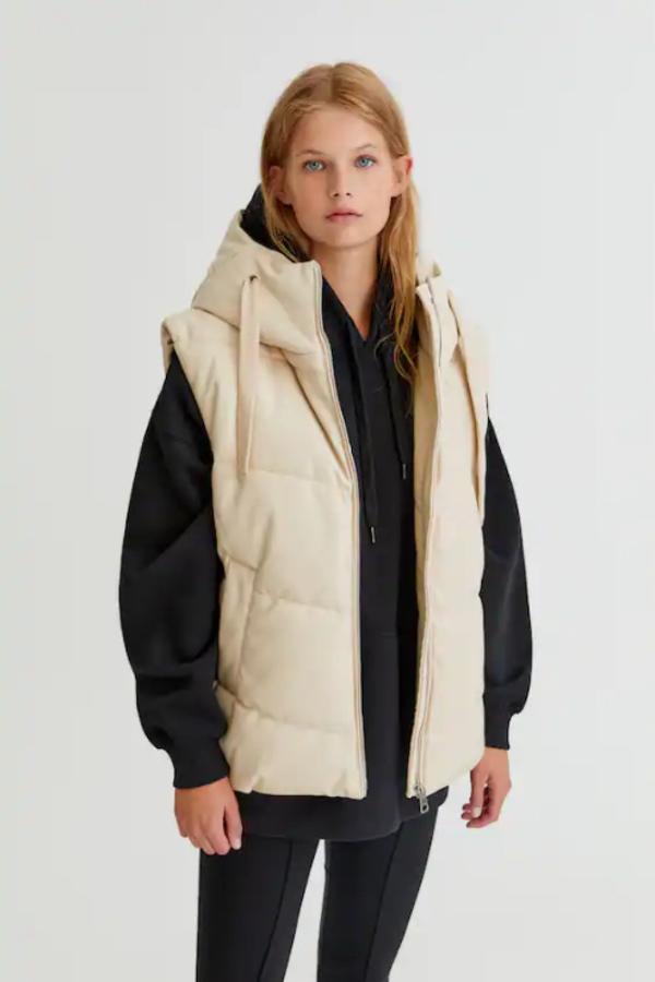 Este chaleco acolchado en efecto piel de Pull&Bear podemos encontrarlo en crudo y en negro. Tiene capucha ajustable con cordones, cierre frontal de cremallera y bolsillos laterales y cuesta 35,99 euros. 